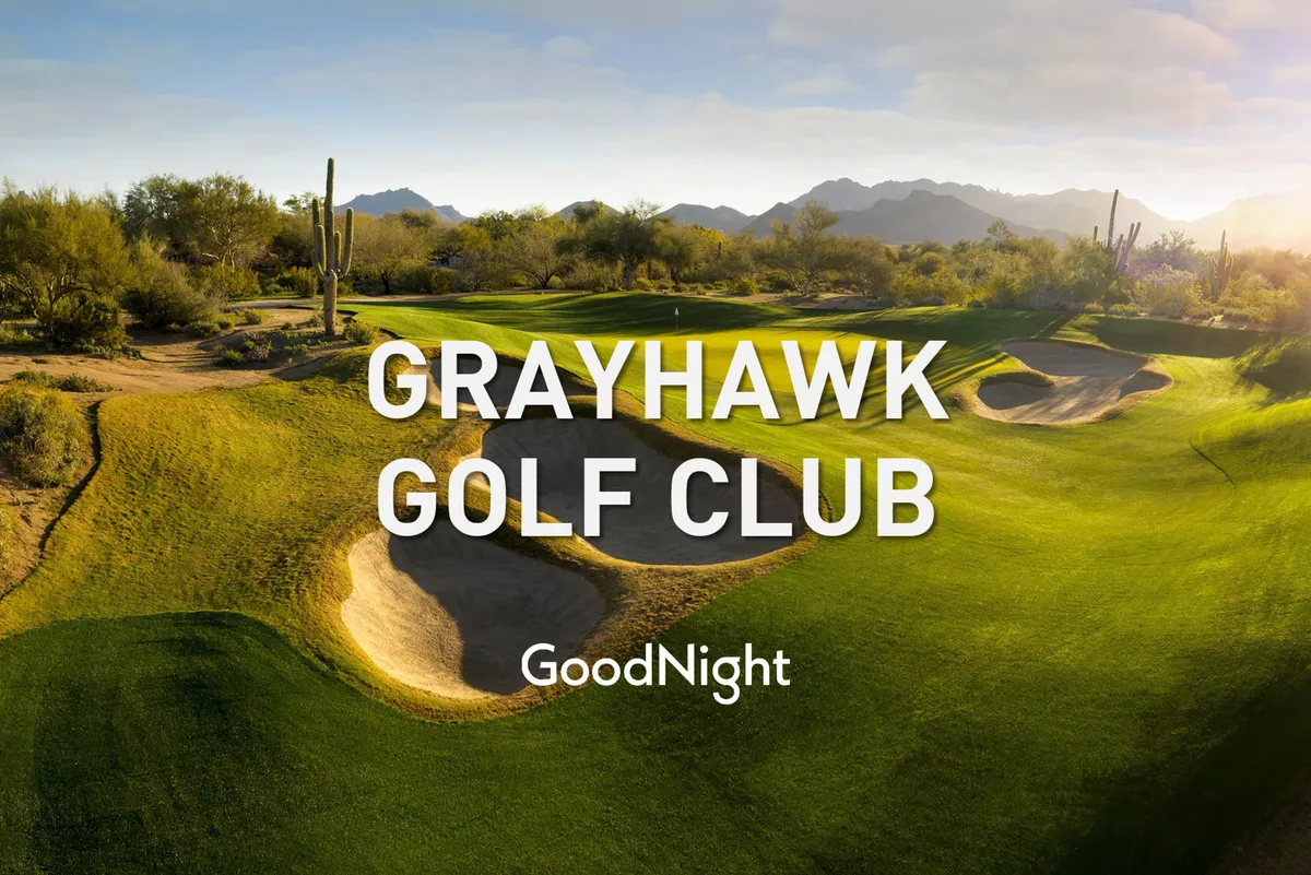 A breathtaking view of a golf course surrounded by sand traps, cacti, and distant mountain peaks. The lush green fairways contrast strikingly with the desert landscape, evoking a sense of serene luxury and outdoor adventure.